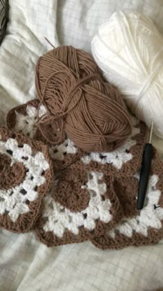 two crocheted afghans and a ball of yarn sitting on a bed next to each other