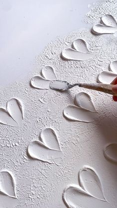 someone is painting hearts on the wall with white paint