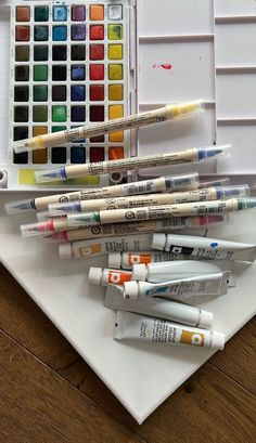 several crayons are sitting on a table next to some watercolors