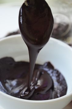 a spoon full of chocolate sauce in a white bowl