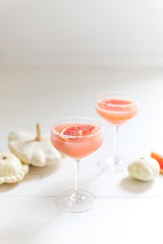 two wine glasses filled with pink grapefruit and garnish