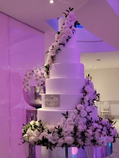 a tall white wedding cake with flowers on it