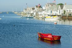 a red boat floating on top of a body of water next to small white houses