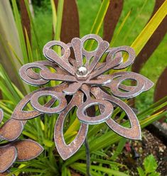 a metal flower sitting on top of a green plant