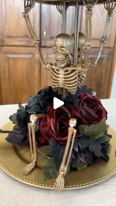 a skeleton sitting on top of a golden plate with flowers in front of it,