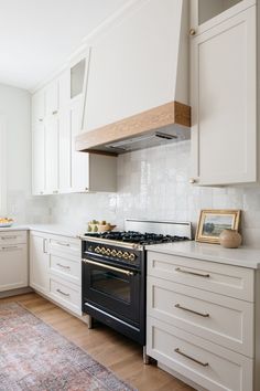 a kitchen with white cabinets and an oven in the center, along with a rug on the floor