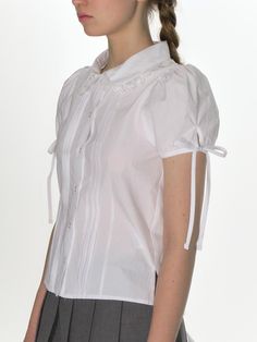 This product is a finely crafted blouse with a lace collar that exudes a vintage charm. It features pintuck detailing along the front, adding texture and a delicate femininity to the overall design. The short sleeves with tie details offer a customizable fit and contribute to the blouse's romantic and timeless appeal.
 
- This blouse is adorned with a lace collar that frames the neckline beautifully, creating a subtle statement.- Pintuck details provide a structured yet soft appearance, enh Spring Blouse With Detachable Collar For Daywear, Elegant Blouse With Detachable Collar For Spring, Fitted Blouse With Broderie Anglaise, Fitted Broderie Anglaise Blouse, Classic Spring Blouse With Detachable Collar, Fitted Broderie Anglaise Short Sleeve Top, Fitted Short Sleeve Top With Broderie Anglaise, Elegant Summer Tops With Peter Pan Collar, Elegant Peter Pan Collar Top For Summer