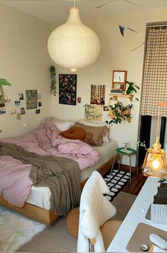 a bed room with a neatly made bed next to a computer desk and lamp hanging from the ceiling