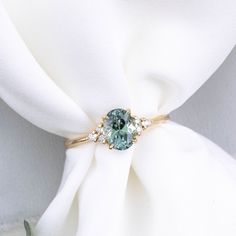 a ring with a blue stone on it sitting on top of a white cloth napkin