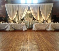 an empty dance floor is decorated with white drapes