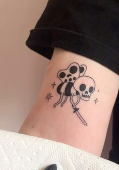 a person with a tattoo on their arm holding two skulls and a knife in the other hand