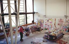 an artist's studio with lots of paintings on the walls