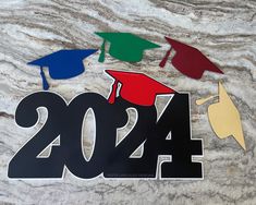 graduation decorations are displayed on a marble surface with the number twenty four in black, red, green, blue and yellow