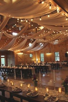 a banquet hall with tables and chairs covered in white draping, lit by candles