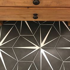 a black and white tiled floor next to a wooden table with drawers on it's sides