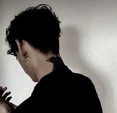 a man with black hair and piercings holding his hands together