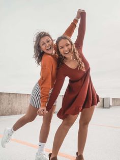 two young women are dancing together in the street