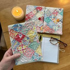 a hand holding a piece of paper next to a notebook and pen on a table