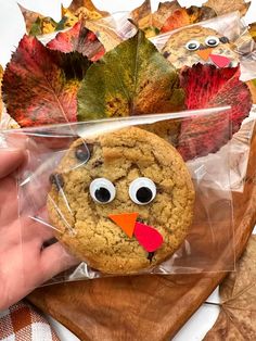 a cookie with googly eyes and a turkey face is in a clear plastic bag