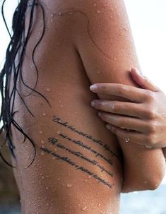 the back of a woman's body with writing on it and water in the background