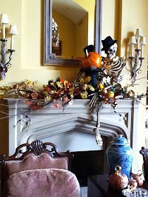 a living room filled with furniture and a fire place covered in halloween decorations next to a mirror