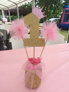 a pink and gold number one centerpiece on top of a table at a birthday party