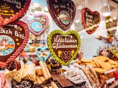 several heart shaped cookies hanging from strings in a store window with german words on them