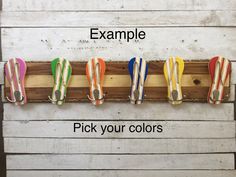 four pairs of colorful shoes hanging on a wooden rack with the words example pick your colors