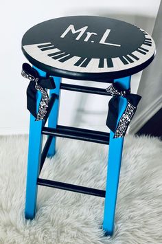 a blue stool with a black and white piano design on the top that says mr l