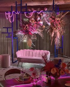 a pink couch sitting next to a table with flowers and candles on top of it