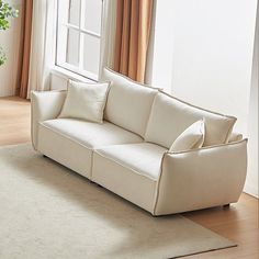 a white couch sitting on top of a wooden floor next to a potted plant