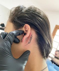 a woman with a tattoo on her left ear and behind the ear is a glove