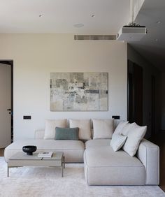 a living room with a white couch and coffee table in front of a painting on the wall