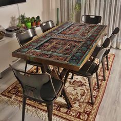 a dining room table with chairs and rug in front of the window, next to a potted plant