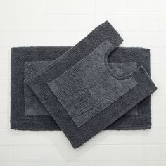 two gray bath mats sitting next to each other