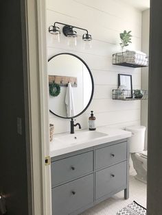 a bathroom with white walls and gray cabinets