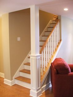 a red chair sitting in front of a stair case next to a white banister