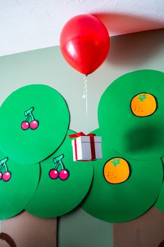 a bunch of green paper circles with fruit on them and a red balloon in the background