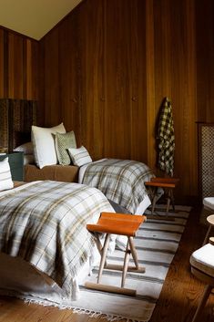 two beds in a room with wood paneling on the walls and wooden flooring