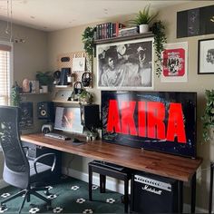 a desk with a computer and some pictures on the wall above it in a home office