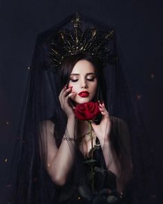 a woman wearing a veil and holding a rose in front of her face, with the dark background