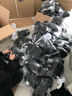 a person sitting on the floor surrounded by boxes and other items that have been wrapped in plastic