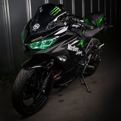 a black and green motorcycle is parked in a garage with its lights turned on at night