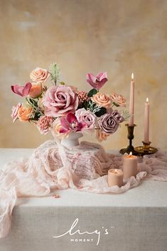 a vase filled with flowers sitting on top of a table next to two lit candles