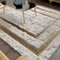 a white rug with gold trimmings on the floor in front of a coffee table