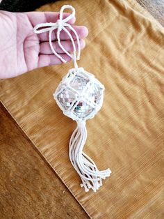 a person is holding a small white ornament on a piece of fabric and string