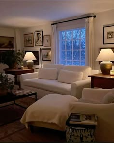 a living room with white furniture and pictures on the wall