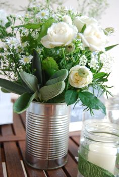 a vase filled with white flowers sitting on top of a table next to a candle