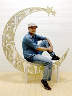 a man sitting on a bench in front of a paper cut out of the moon