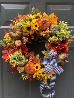 a fall wreath with sunflowers, pumpkins and gourds hanging on the front door